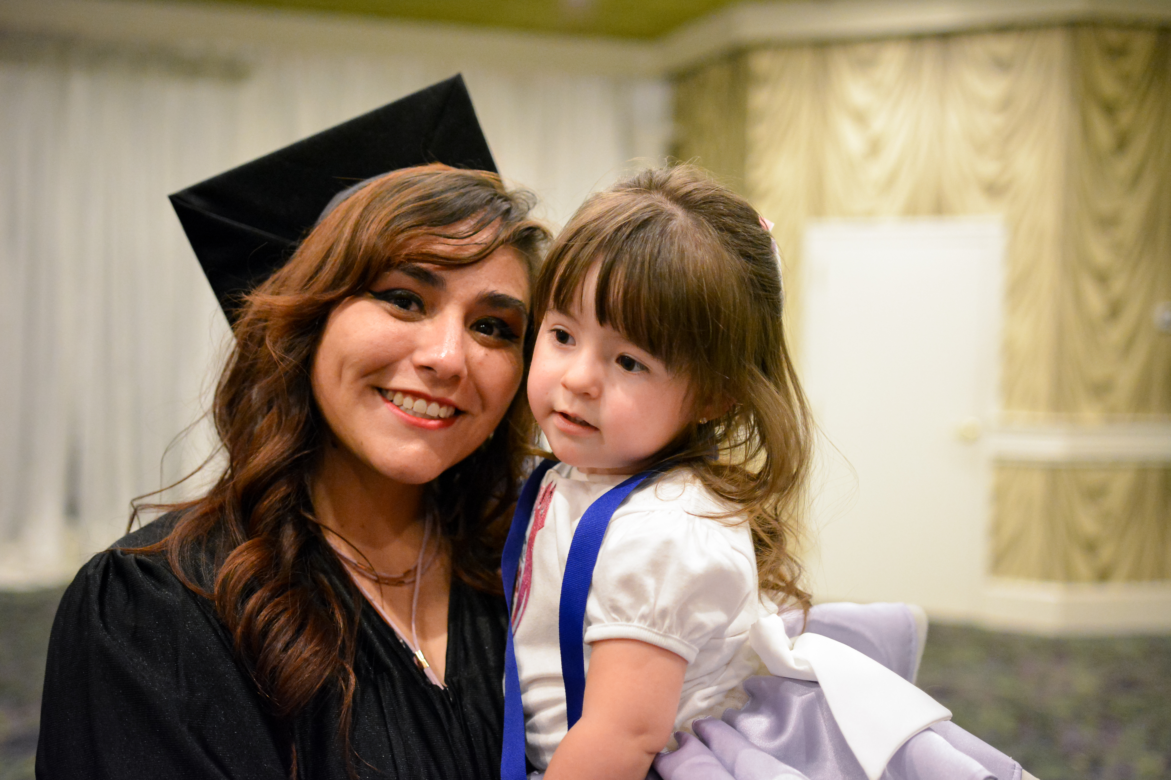 Trainee holding and posing with child at graduation ceremony.